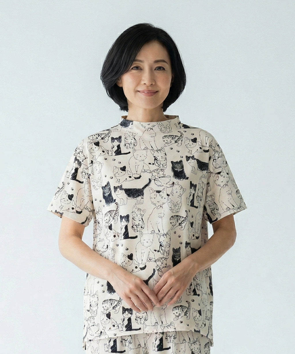クニオコレクション(KUNIO COLLECTION)のチアフルシャーリングPO(アイボリー)。ミルクティ地にしなやかな線画で描かれたネコちゃん柄が爽やかで遊び心溢れるデザインのプルオーバー。裾のゴムでブラウジングや着丈の調節ができ、さらりとした軽いストレッチ素材で移動時も快適なブラウス感覚のトップス。
