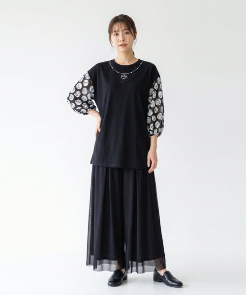 クニオコレクション（KUNIO COLLECTION）のギャザーショルダーチュニック（ドット柄・ブラック）。美しいシルエットと程よいハリ感のあるダブルシルケットスムース素材のボディに、線画を水玉模様にアレンジした遊び心のあるギャザーチュール袖を合わせた大人可愛いチュニックです。胸元には上品なネックレス風のラインと肉球モチーフの刺繍が施されています。女性モデル着用カット。