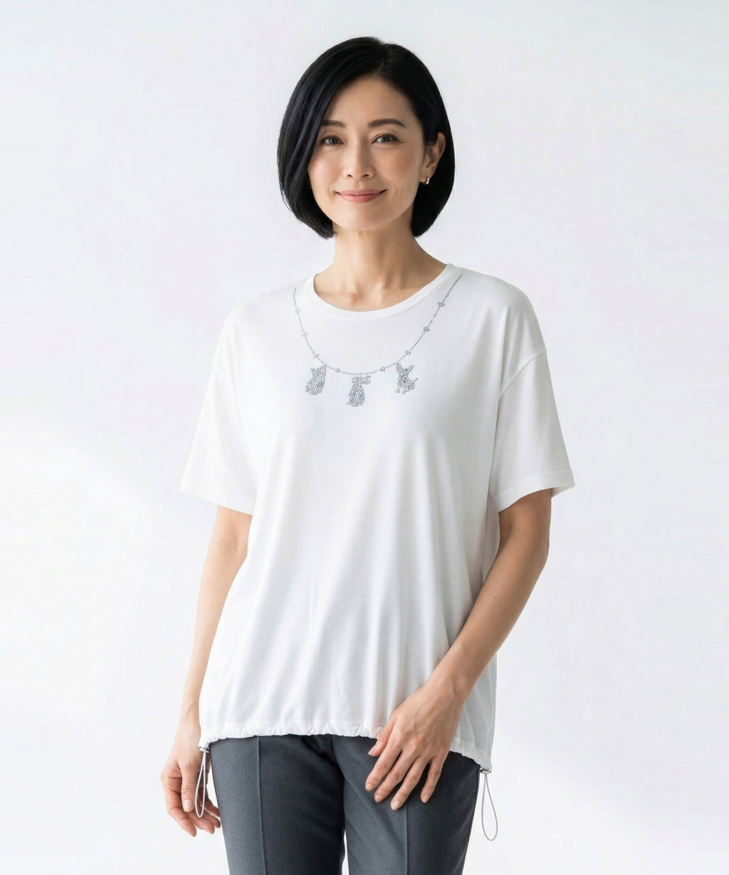 クニオコレクション(KUNIO COLLECTION)のネックレスヘムシャーリングT(ホワイト)。ラインストーンでワンちゃん、ネコちゃん、うさぎちゃんを表現したネックレス柄が特徴のTシャツ。裾のゴムでブラウジングや着丈の調節ができ、UV加工と接触冷感機能を備えた綿レーヨン素材の天然素材トップス。