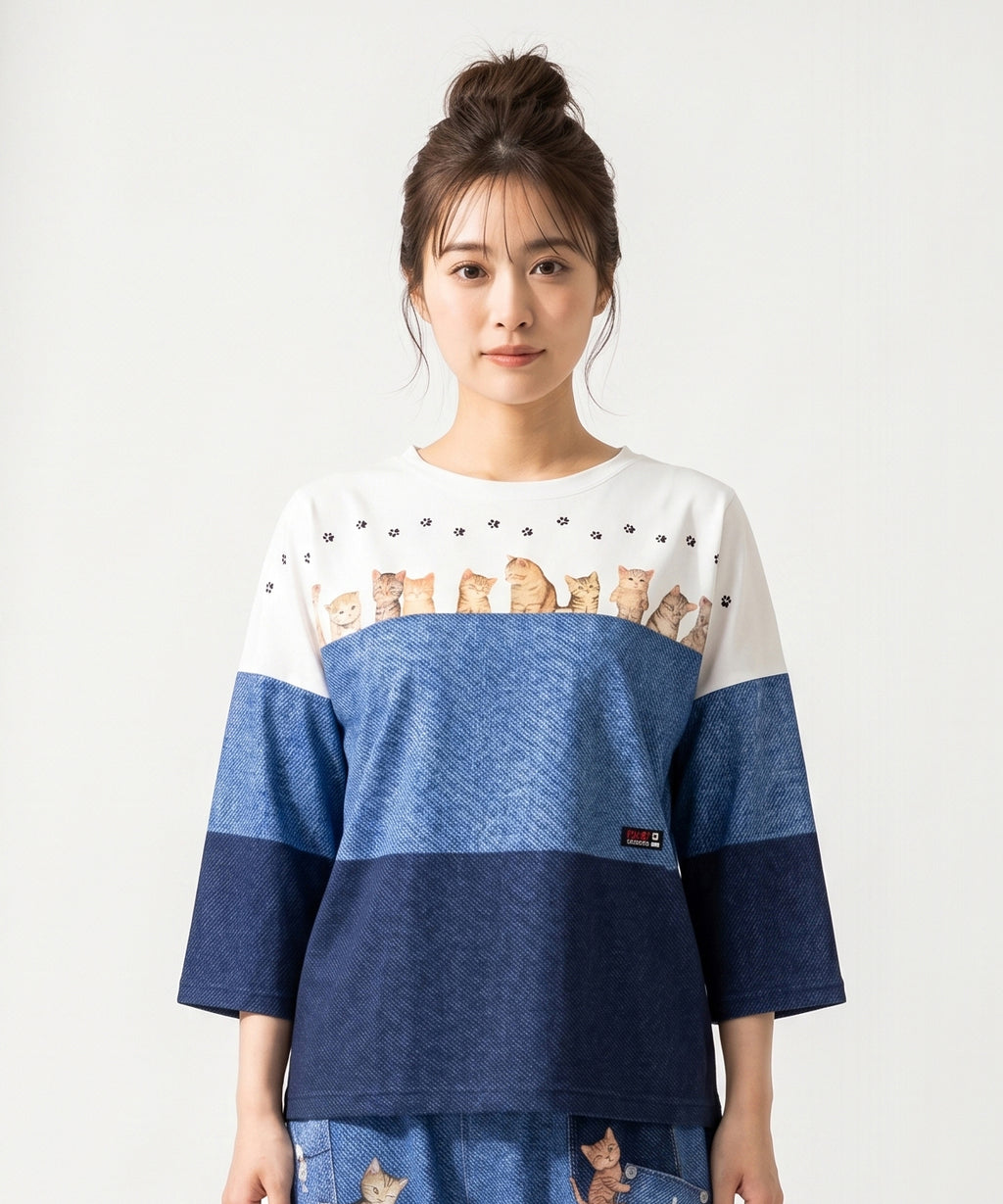 クニオコレクション(KUNIO COLLECTION)のスリーステップ(ネコ)ドルマンTシャツ。バイカラーデニム風のデザインに愛らしいネコちゃん柄をあしらった、ゆるっとオフボディなシルエットの一枚。さらりとした軽い着心地と心地よいストレッチ素材が特徴のトップス。