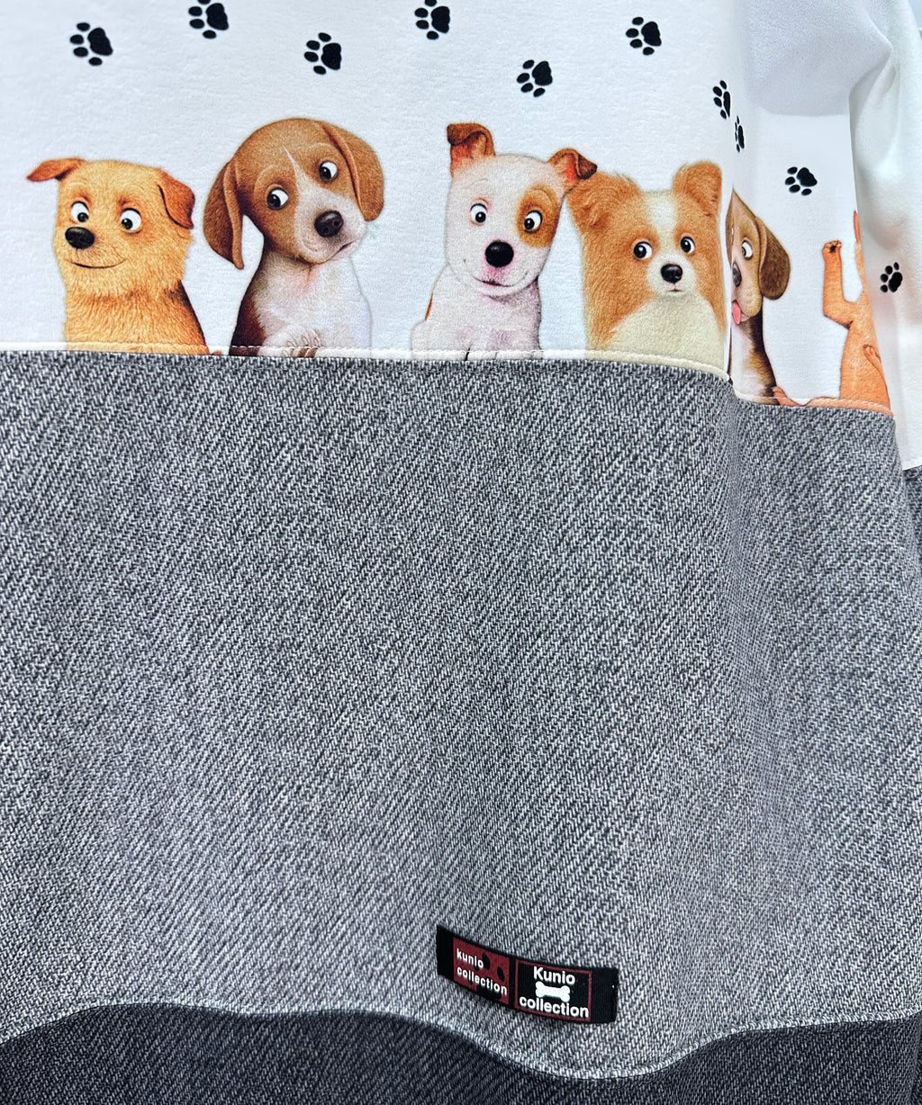 クニオコレクション(KUNIO COLLECTION)のスリーステップ(イヌ)ドルマンTシャツ。バイカラーのブラックデニム風デザインに愛らしいワンちゃん柄をあしらった、ゆるっとオフボディなシルエットの一枚。さらりとした軽い着心地と心地よいストレッチ素材が特徴のトップス。