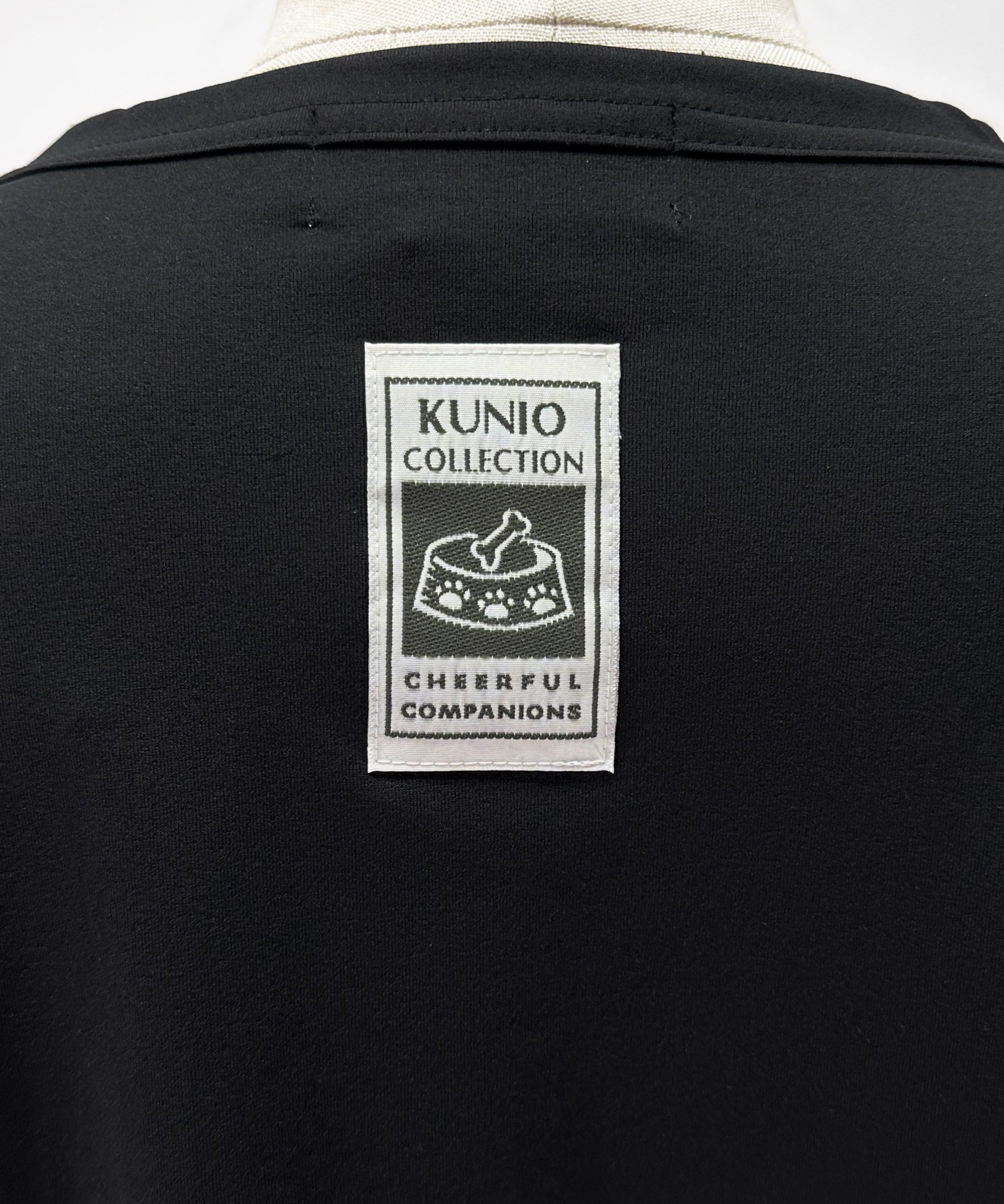 クニオコレクション(KUNIO COLLECTION)のタックT(ブラック)。ロミオとジュリエットをテーマにした可愛いネコちゃんとワンちゃんの作品をストリート調にデザインしたTシャツ。「LET’S GO SLOWLY, AND STEADILY（ぼちぼちいこか）」のメッセージを配し、さらりとした軽い着心地と気持ちの良いストレッチ性を備えた異形糸使用のトップス。